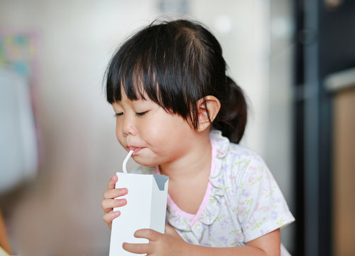 Closeup of little girl drinking milk with straw.