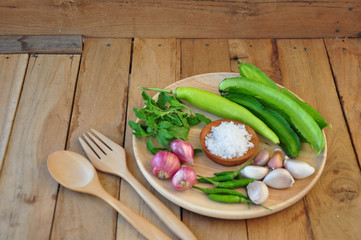 ingradian. vegetable ingradian. red onion, winged bean, besil leaf, garic, chilli and salt is on a wooden plate.