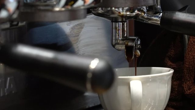 Coffee machine pouring hot coffee into white cup