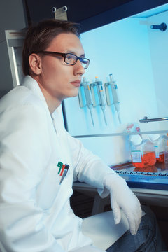 Young Male Scientist Sitting By The Cell Culture Hood