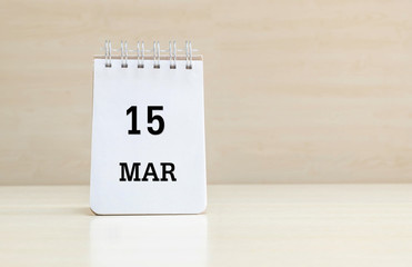 Closeup surface note book with black 15 mar word in page on blurred brown wood desk and wood wall textured background with copy space under window light