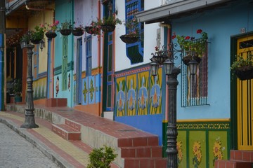 Fototapeta na wymiar Hanging basket flowers, street lamps and wooden doors and window frames of a colorful little cosy street in Guatape, Colombia.