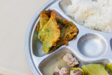 closeup stainless tray with rice, omelette and soup, shallow depth of field.