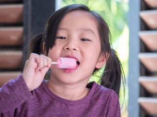 Little Asian girl eating ice cream, wood shade stripes background