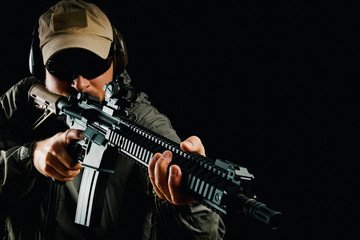 man in cap and jacket keeps assault rifle