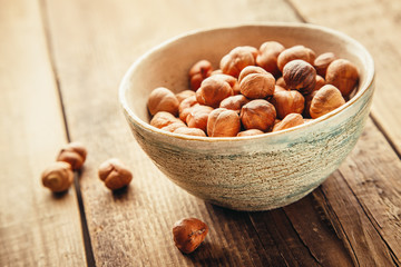Hazelnuts in a bowl, wooden background. Shallow DOF
