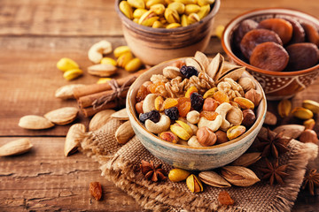 Mix of nuts and dried fruits on a old rustic table. Gold pistachios, cashews, hazelnuts, almonds.