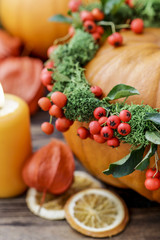 Pumpkin decorated with wreath with red berries (cotoneaster horizontalis) and green moss.