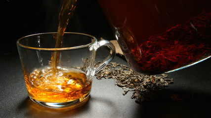 Hot tea pours to a cup from a teapot