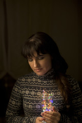 Young woman with garlands in cup on dark background