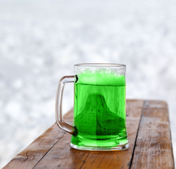 Full fresh cold glass of green beer on wooden bench