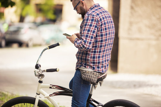 Young Man Sitting On Bike Using Mobile