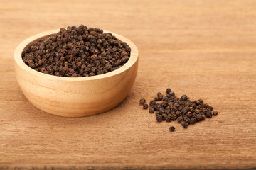 black peppercorns in wooden bowl