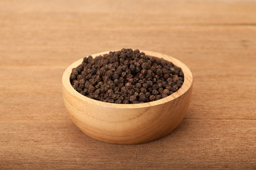 Fototapeta na wymiar black peppercorns in wooden bowl