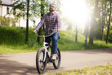 Fototapeta premium Young modern man riding bike in park thinking