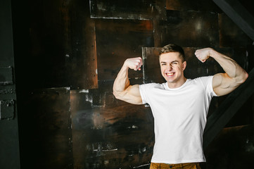 Young sexy men bodybuilder athlete, studio portrait in a loft on a background of  stylized metal...