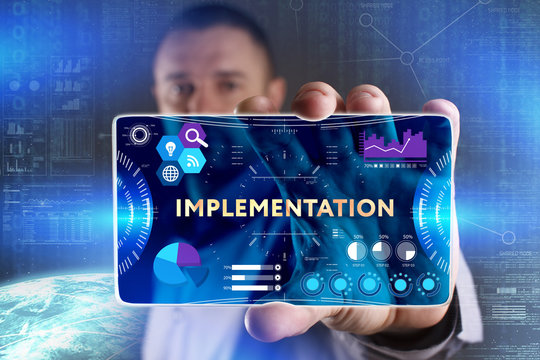 Business, Technology, Internet and network concept. Young businessman showing a word in a virtual tablet of the future: Implementation