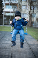 Little boy swinging on swing at children playground