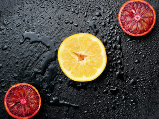 Slice of red, blood , cicilian orange and lemon on wet slate plate wiht a lot of water drops.Copy...