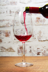 Glass of full bodied red wine being poured