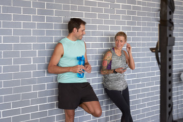 Fototapeta na wymiar Gym friends talking leaning against brickwall 