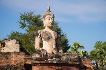 Ancient sculpture of a seated Buddha on the ruins of a Buddhist temple, Wat Mae Chon sunny day. Sukhothai, Thailand