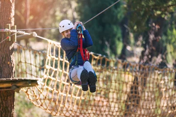 Foto auf Leinwand Happy school girl enjoying activity in a climbing adventure park on a summer day © Mediteraneo