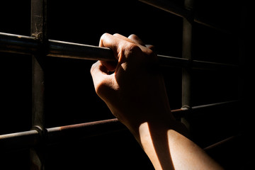 Close up Man hands are holding the cage door in dark room