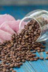 Close-up of coffee cup with roasted coffee beans on wooden background.