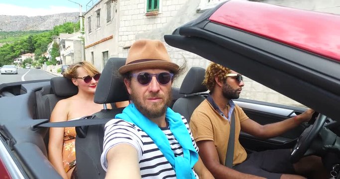 Four young friends enjoying their road trip in convertible car