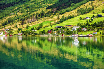 Natural rural landscape. Town and cruise port Olden in Norwegian fjords. Tourist camping on the beach.