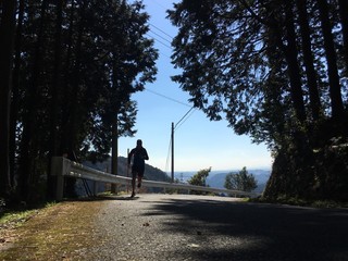 Silhouette of man running uphill on country road 