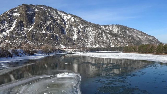 Aerial view on Altai river Katun with  floating of ice  in water and mountains on background in winter season