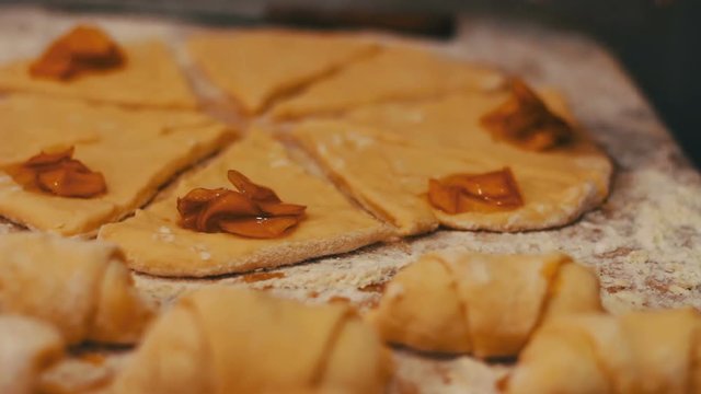 A woman puts on fresh pieces of dough apricot jam