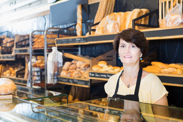 Woman baker with bread products on counter in bakery