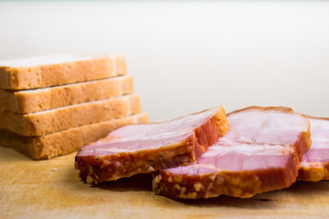 Raw smoked bacon slices with bread on wooden board