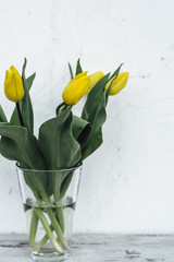 Bunch of yellow tulips in vase on wooden table