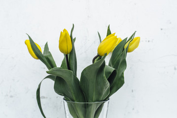 Fototapeta premium Bunch of yellow tulips in vase on wooden table