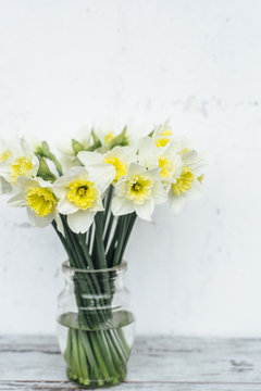 Bunch of narcissus in transparent vase on wooden table
