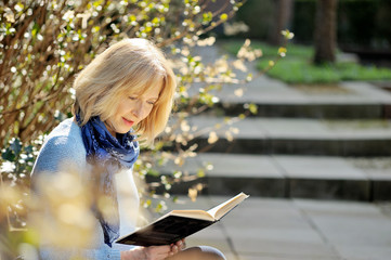 Seniorin liest ein Buch auf der Parkbank
