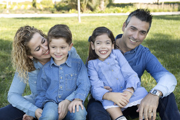 Family sitting on the lawn of a park.