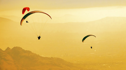 Paragliders in flight in summer at sunset