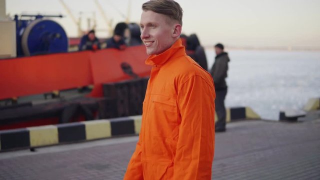 Dock worker in orange uniform walking in the harbor and controlling working process in the port.