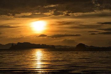 Naklejka na ściany i meble Sunset over the sea at Ao Nang, Krabi, Thailand. Dusk at the beach, orange sky with clouds.