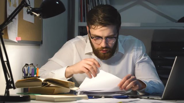 Concentrated business man working with documents on his desk in office late 