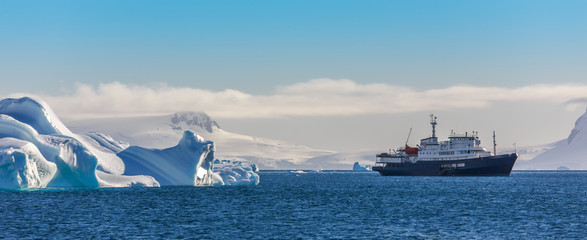 Blue cruise vessel among the icebergs with glacier in background, South Shetland Islands, Antarctica