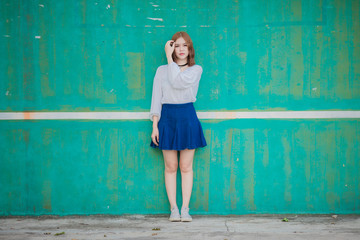 Fototapeta premium Portrait of young hipster Asian girl posing in the Dirty blue wall background