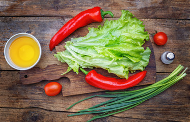 .Salad, pepper, green onion,  oil, salt on a rustic wooden table.