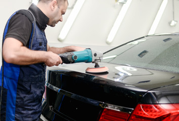 Naklejka na ściany i meble Man on a car wash polishing car with a polish machine