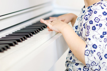 Beautiful little kid girl playing piano in living room or music school
